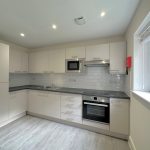 Modern kitchen with white cabinets and appliances.
