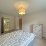 Bedroom with bed, dresser, and open bathroom door