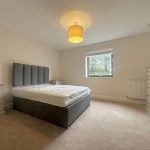 Modern bedroom with double bed and window view.