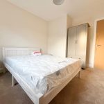 Minimalist bedroom with bed, wardrobe, and bedside table.