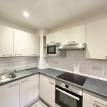 Modern kitchen with white cabinets and appliances.