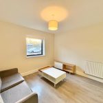 Minimalist living room with grey sofa and table.