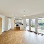 Spacious modern kitchen with wooden floor, large windows.