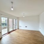 Bright empty room with wooden floor and large windows.