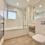 Modern white bathroom with toilet, sink, and bathtub.