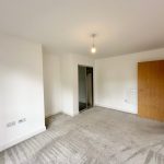 Empty room with carpet, door, and wardrobe.