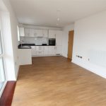 Modern kitchen with wooden flooring and white cabinets.