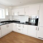 Modern white kitchen with black countertops.