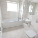 Modern white bathroom with bathtub and mirror.
