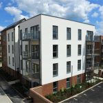 Modern residential building with balconies and parking area.