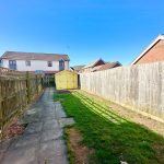 Backyard with wooden fences and a yellow shed.