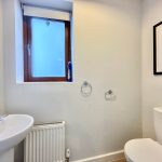 Modern bathroom with window, sink, and toilet.