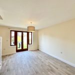 Bright empty room with wooden flooring and glass door.