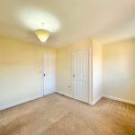 Empty room with beige carpet and lamp.