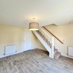 Empty room with stairs and wooden flooring.
