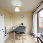 Dining room with table, chairs, clock, and fridge.