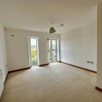Empty room with beige carpet and big windows.