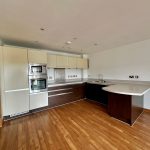 Modern kitchen with wood flooring and appliances.
