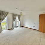 Empty carpeted room with large window and door.