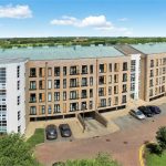 Modern apartment complex with parking and greenery.