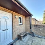 White door on brick wall with outdoor bench.