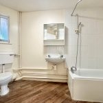 Minimalist bathroom with toilet, sink, and bathtub.