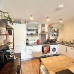 Modern kitchen with wooden table and open shelves.