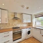 Modern kitchen with wooden countertops and white cabinets.