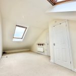 Bright attic room with skylight and white walls.