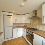 Modern kitchen with wooden worktops and tile backsplash.