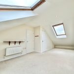 Bright attic room with skylights and white walls.