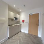 Compact modern kitchenette with microwave and worktop.