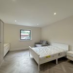 Modern bedroom with bed, wardrobe, and sofa.