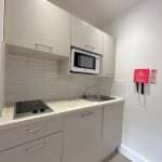 Compact kitchen with microwave and sink.