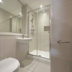 Modern bathroom with shower and white tiles.
