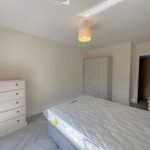 Minimalist bedroom with bed, wardrobe, and chest of drawers.