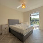 Bright bedroom with double bed and window view.