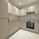 Modern kitchen with light cabinetry and built-in oven.