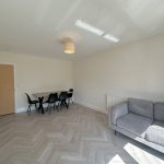 Minimalist living room with grey sofa and dining table.