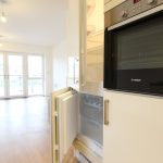 Modern kitchen with open fridge and large windows.