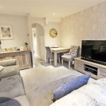Bright living room with grey sofa and TV.