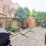 Garden patio with shed and outdoor furniture.