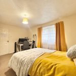 Cosy bedroom with desk and yellow accents.