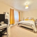 Cosy bedroom with desk, bed, and decor.