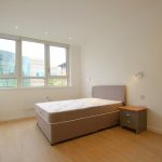 Modern bedroom with bed and large window view.