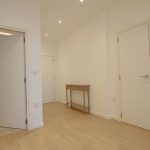 Minimalist hallway with light wooden flooring.