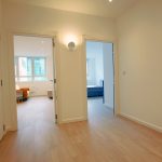 Bright hallway leading to two rooms with wood flooring.
