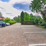 Residential car park with brick paving and trees.