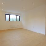 Spacious empty room with wooden floor and window.