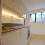 Modern kitchen with light cabinetry and wooden flooring.